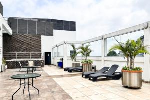 an outdoor patio with chairs and tables on a building at Lujoso Depa con piscina - jacuzzi y vista al rio desde la habitación in Guayaquil
