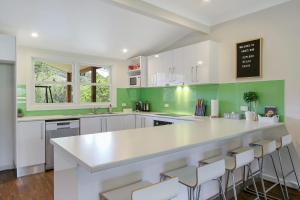 uma cozinha com armários brancos e uma parede verde em Indie's Run em Wandiligong
