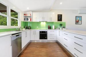 una cocina con armarios blancos y paredes verdes en Indie's Run, en Wandiligong 15 fotos más
