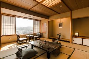 a living room with a table and chairs and a large window at かっぱの宿旅館三治郎 in Zao
