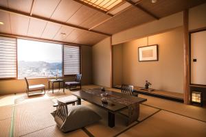 a living room with a table and chairs and a large window at かっぱの宿旅館三治郎 in Zao