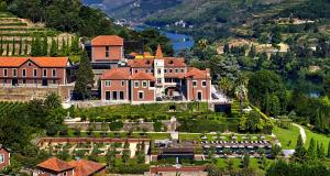 un grand manoir sur une colline avec un lac dans l'établissement Six Senses Douro Valley, à Lamego