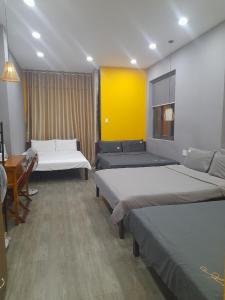 a room with two beds and a table and a desk at Thanh Hằng Homestay in Can Tho