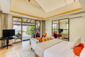 a bedroom with a large bed and a living room at Cinnamon Hakuraa Huraa Maldives - All Inclusive in Meemu Atoll