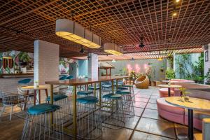 a restaurant with a bar with stools and tables at Liberta Seminyak Hotel in Seminyak