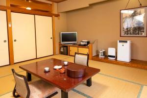 静かなお宿加賀美 في Shimojo mura: غرفة معيشة مع طاولة وتلفزيون