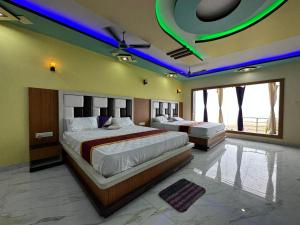 Duas camas num quarto grande com luzes roxas em ST Apple Beach Resort Mandarmani em Mandarmoni