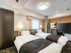 a hotel room with two beds and a desk at APA Hotel Niigata Tsubame-Sanjo Ekimae in Tsubame