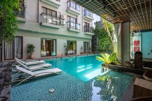 a swimming pool with lounge chairs next to a building at Liberta Seminyak Hotel in Seminyak