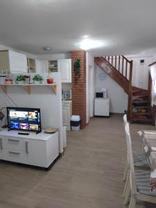 a living room with a television and a staircase at Marina Cottage in Enying