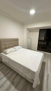 a bedroom with a large white bed and a flat screen tv at Hermoso departamento de estreno con piscina in Lima