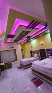 a room with two beds and purple lights on the ceiling at ST Apple Beach Resort Mandarmani in Mandarmoni