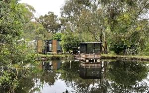 a house is sitting on the water near a lake at Longmore Estate in Daylesford