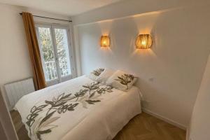 a bedroom with a bed and two lights on the wall at Appartement T2 Petite Jade in Luchon
