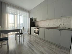 uma cozinha com armários brancos e uma mesa e cadeiras em ЖК Sati Club House em Prigorodnyy