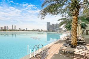 einen Pool mit einer Palme neben einer Stadt in der Unterkunft LUX - Opulent Island Suite Burj Khalifa View 1 in Dubai