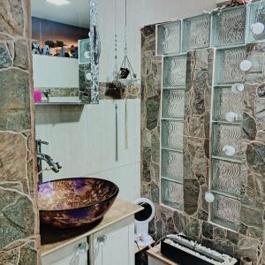 baño con lavabo y pared de piedra en Casa Raices en Quito