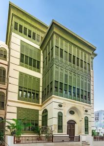 a large building with green windows on a city street at Al Balad Hospitality in Jeddah