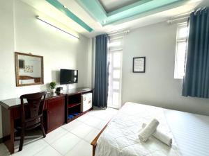 een slaapkamer met een bed, een bureau en een televisie bij khách sạn Kim Long in Ho Chi Minh-stad