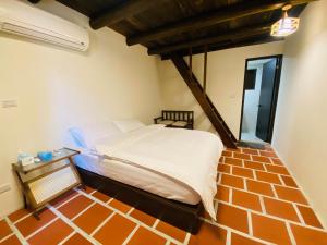 a bed in a room with a brick floor at Wuzou Guesthouse in Jinsha