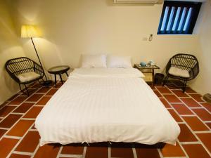 a bedroom with a large white bed and two chairs at Wuzou Guesthouse in Jinsha
