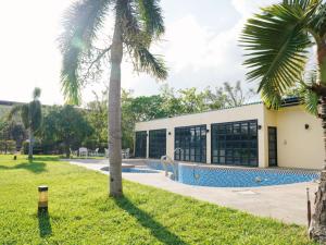 a building with a swimming pool and a palm tree at Dan Lee Inn in Hengchun South Gate