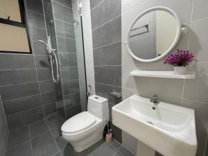 La salle de bains est pourvue de toilettes, d'un lavabo et d'un miroir. dans l'établissement Ipoh Waterpark The Cove Premium Suites 7-13pax by IWH, à Ipoh