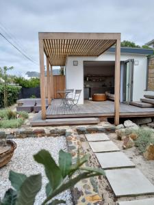 patio trasero con terraza de madera en Quaint Cottage en Hermanus