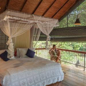 a woman sitting in a chair in a bedroom at The River House Dambulla by The Serendipity Collection in Dambulla