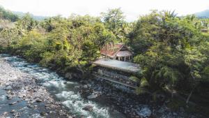 une maison à côté d'une rivière bordée d'arbres et d'une rivière gmaxwell gmaxwell dans l'établissement Darmada Eco Resort, à Sidemen