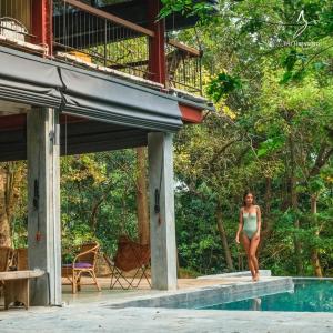 a woman in a bikini standing next to a swimming pool at The River House Dambulla by The Serendipity Collection in Dambulla