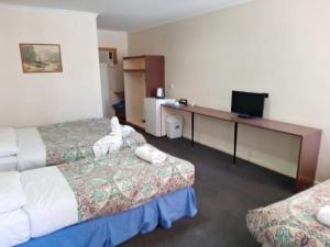ein Hotelzimmer mit 2 Betten und einem Schreibtisch in der Unterkunft Austral Inn in Quorn