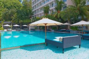 ein Pool mit Sonnenschirm und Stühlen sowie ein Hotel in der Unterkunft Quiet Beach 1 BR Beach View NE28 in Teluk Nara
