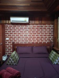 uma cama num quarto com uma parede de tijolos em Lanta Yoky bangalow em Phra Ae beach