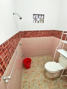 a bathroom with a toilet and a red bucket at AMAZEN Lodge and Resort in Busuanga