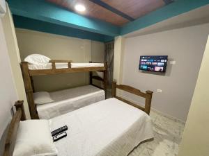 a room with two bunk beds and a flat screen tv at Villa Carolina SM in Santa Marta