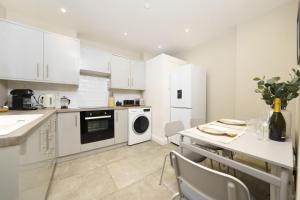 a kitchen with white cabinets and a table with a dishwasher at Best Covent Garden/Chinatown/Soho Location in London