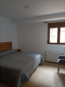 a white bedroom with a bed and a window at Apartamentos Rurales La Capellanía de Alobras in Alobras