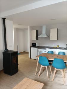 uma cozinha com uma mesa de madeira e cadeiras azuis em Apartamentos Rurales Fuente del Peral em Alobras