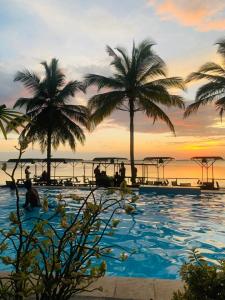 a resort swimming pool with palm trees and the ocean at New Saniro Lagoon Deck in Katunayake
