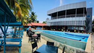 a swimming pool with tables and chairs next to a building at New Saniro Lagoon Deck in Katunayake