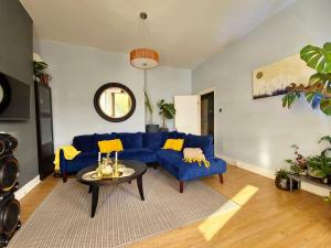 a living room with a blue couch and a table at Hidden Gem - One bedroom flat with private garden in Plumstead