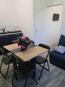 a dining room table with a vase of flowers on it at Le Studio in Saint-Pierre-Montlimart