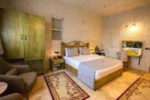 a bedroom with a bed and a chair and a mirror at Majestic Cave House in Nevsehir