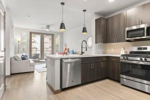 a kitchen with stainless steel appliances and a living room at Cozysuites PHX RORO Gym, Pool, Pets, Parking! #7 in Phoenix