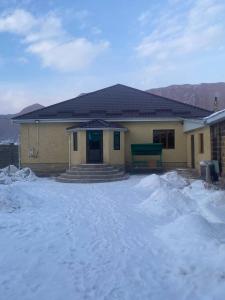 ein Haus mit Schnee davor in der Unterkunft Monchok Guest House in Naryn