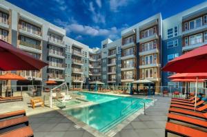 an apartment complex with a swimming pool and red umbrellas at Cozysuites PHX RORO Gym, Pool, Pets, Parking! #10 in Phoenix