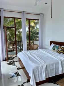 a bedroom with a bed and a large window at Coconut Palm beach restaurant and rooms in Dickwella