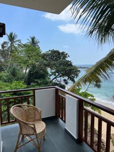 Un balcón con una silla y vistas al océano. en Coconut Palm beach restaurant and rooms en Dikwella South