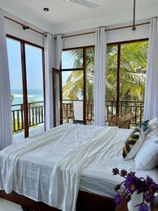 a bedroom with a bed with a view of the ocean at Coconut Palm beach restaurant and rooms in Dickwella